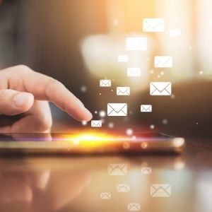 Eine Hand berührt ein Smartphone-Display mit illustrierten E-Mail-Symbolen, die nach oben schweben und das Senden oder Empfangen digitaler Nachrichten symbolisieren - perfekt, um Jobcoaching München in der heutigen vernetzten Welt zu repräsentieren.