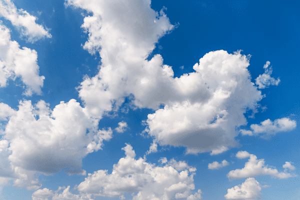 Ein strahlend blauer Himmel, gefüllt mit verstreuten, flauschigen weißen Wolken verschiedener Formen und Größen an einem sonnigen Tag.