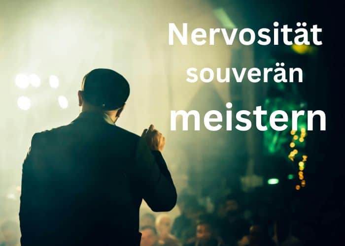 Eine Person im Anzug steht mit einem Mikrofon in der Hand auf der Bühne und blickt ins Publikum. Der Text auf dem Bild lautet: „Nervosität souverän meistern“. Der Hintergrund ist unscharf, man erkennt Lichter und Menschen.